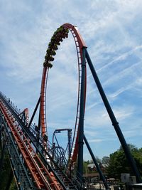 Low angle view of ferris wheel against cloudy sky