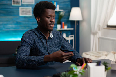 Young man using mobile phone while sitting on table