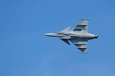 Low angle view of airplane flying against clear blue sky