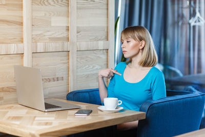 Side view of young woman using laptop at home