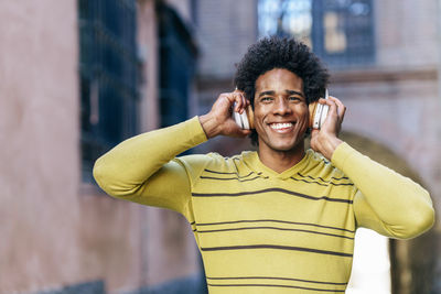 Smiling man listening musing standing outdoors