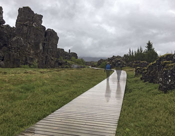 Footpath amidst stone wall against sky