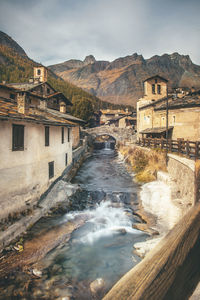 View of river flowing amidst building against mountain