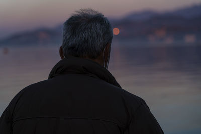 Rear view of man looking at sea against sky