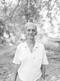 Portrait of smiling man standing against trees