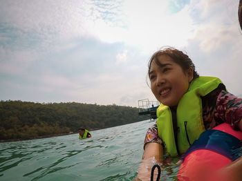 Portrait of smiling boy against water against sky