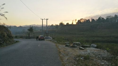 Cars on road against sky during sunset