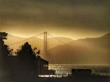 View of suspension bridge in city at sunset