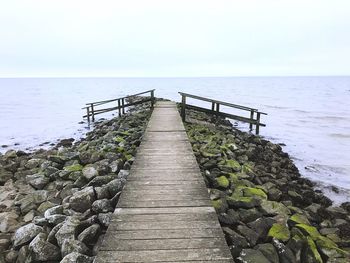 Jetty leading towards sea against clear sky