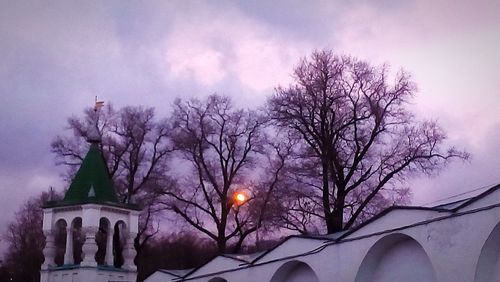 Low angle view of bare trees against cloudy sky