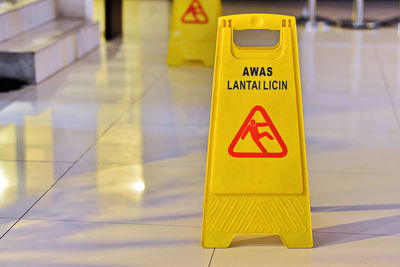 Close-up of warning sign on tiled floor
