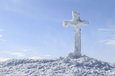 Low angle view of cross against sky during winter