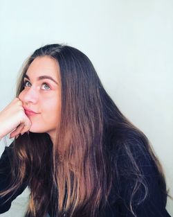  thoughtful young woman with hand on chin against white background