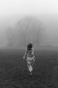 Rear view of woman on field during foggy weather