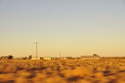 Electricity pylon on field against clear sky during sunset