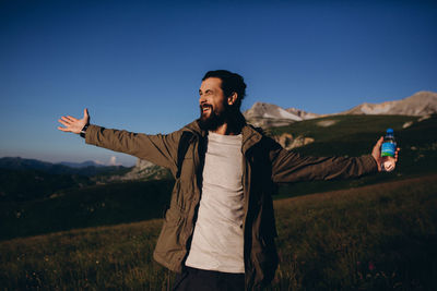 Young man with arms outstretched standing on field