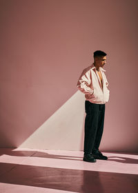 Young man looking away against wall