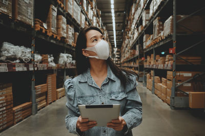 Woman wearing mask examining warehouse