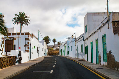 Road amidst buildings against sky