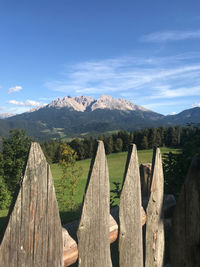 Wooden fence by mountains against sky