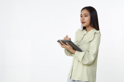 Young woman using smart phone against white background