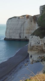 Rock formations by sea against clear sky