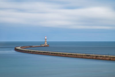 Lighthouse by sea against sky