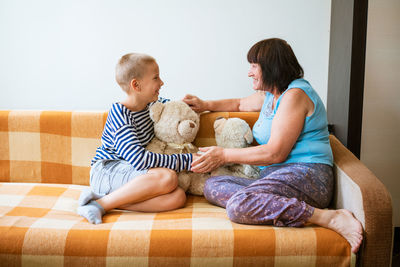 Mother and daughter sitting on sofa at home