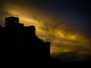 Low angle view of silhouette building against sky at sunset