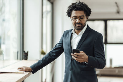 Businessman with curly hair using mobile phone in office