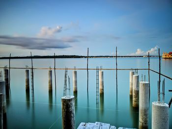 Wooden posts in sea against sky