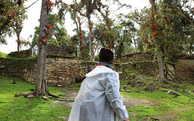 Rear view of man wearing raincoat standing on field