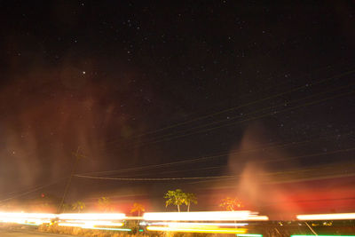 Low angle view of light trails against sky at night