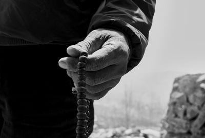 Midsection of man holding prayer beads