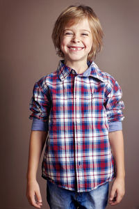 Portrait of smiling boy standing against gray background