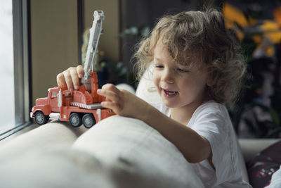 Boy playing with toy while sitting on sofa at home