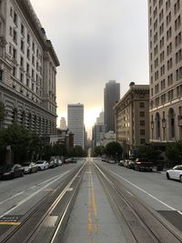 Cars on road in city against sky