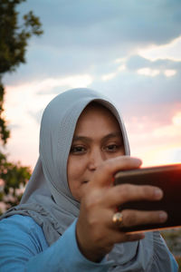 Woman taking selfie with mobile phone against sky