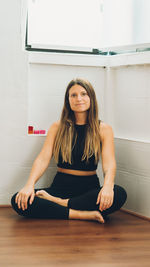 Portrait of young woman sitting on hardwood floor at home