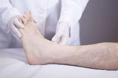 Midsection of doctor examining patient barefoot in hospital