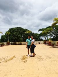 Full length rear view of couple walking against sky