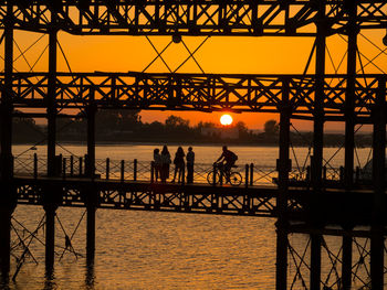 Silhouette people on pier over sea against sky during sunset