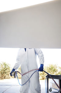 Midsection of engineer holding sander while standing by airplane wing at industry