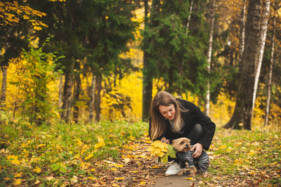 Young woman with dog in forest during autumn