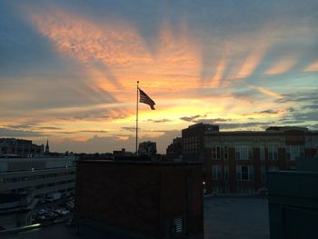 Flag in city against sky during sunset