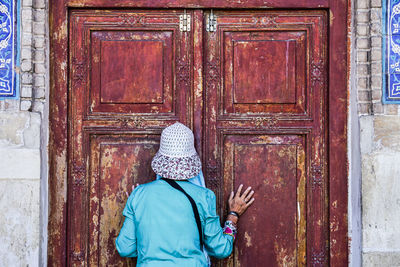 Rear view of woman standing against closed door of building