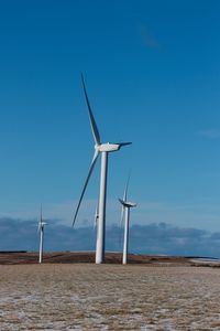 Windmill on wind turbines against blue sky