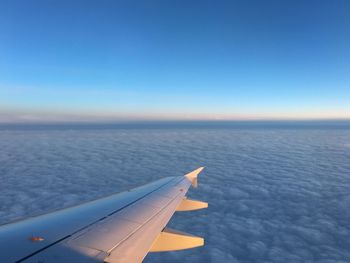 Cropped image of airplane wing over cloudscape