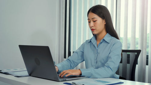 Young woman using mobile phone while sitting on table