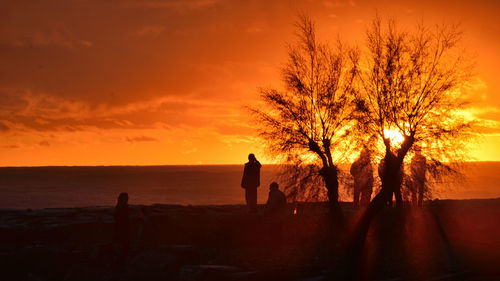 Silhouette people on beach against sky during sunset